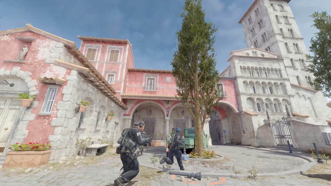 Counter-Strike 2'de renkli binaların arasındaki bir meydanda ilerleyen iki oyuncu
